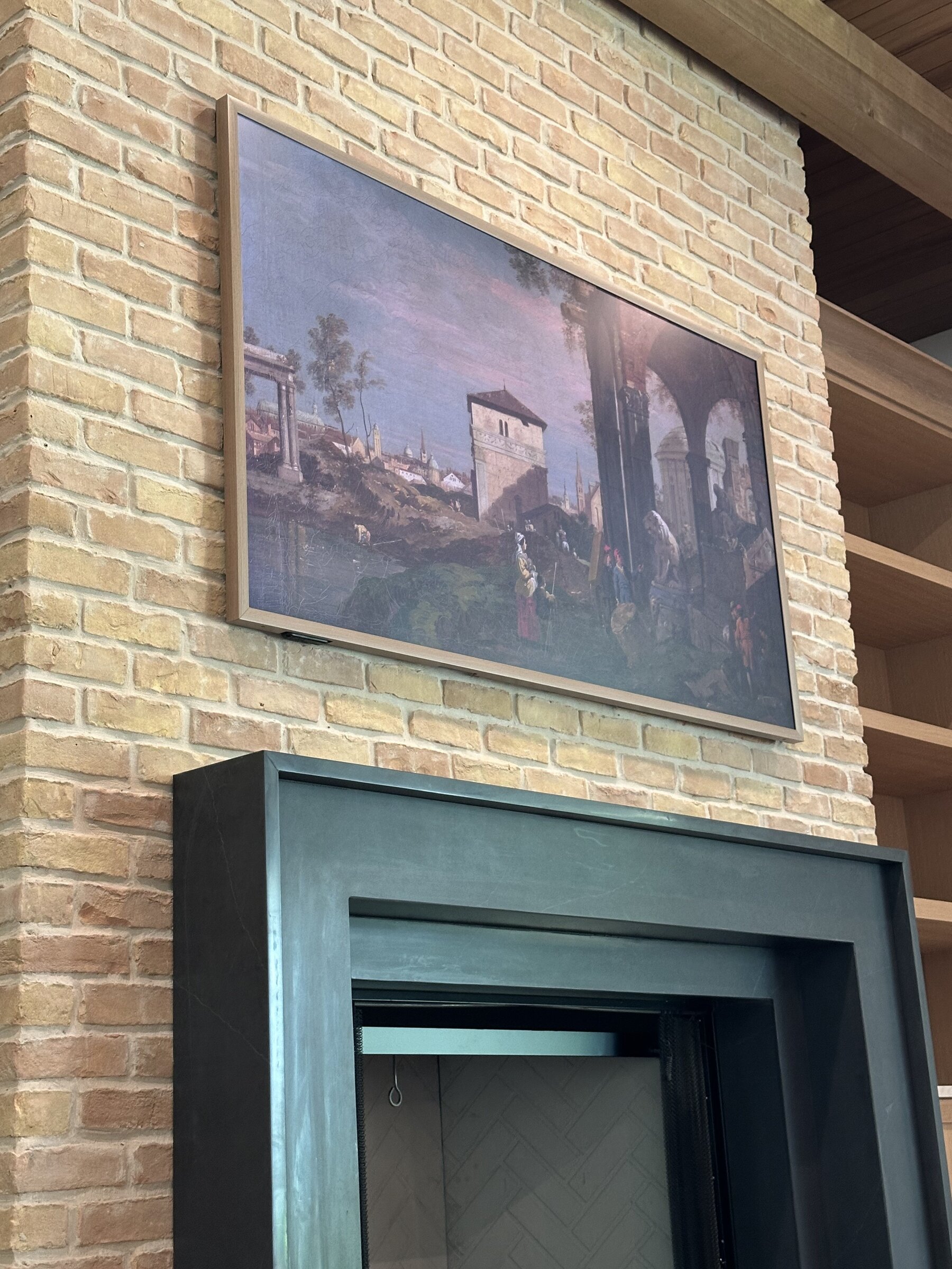 Frame TV displaying art above a stone fireplace