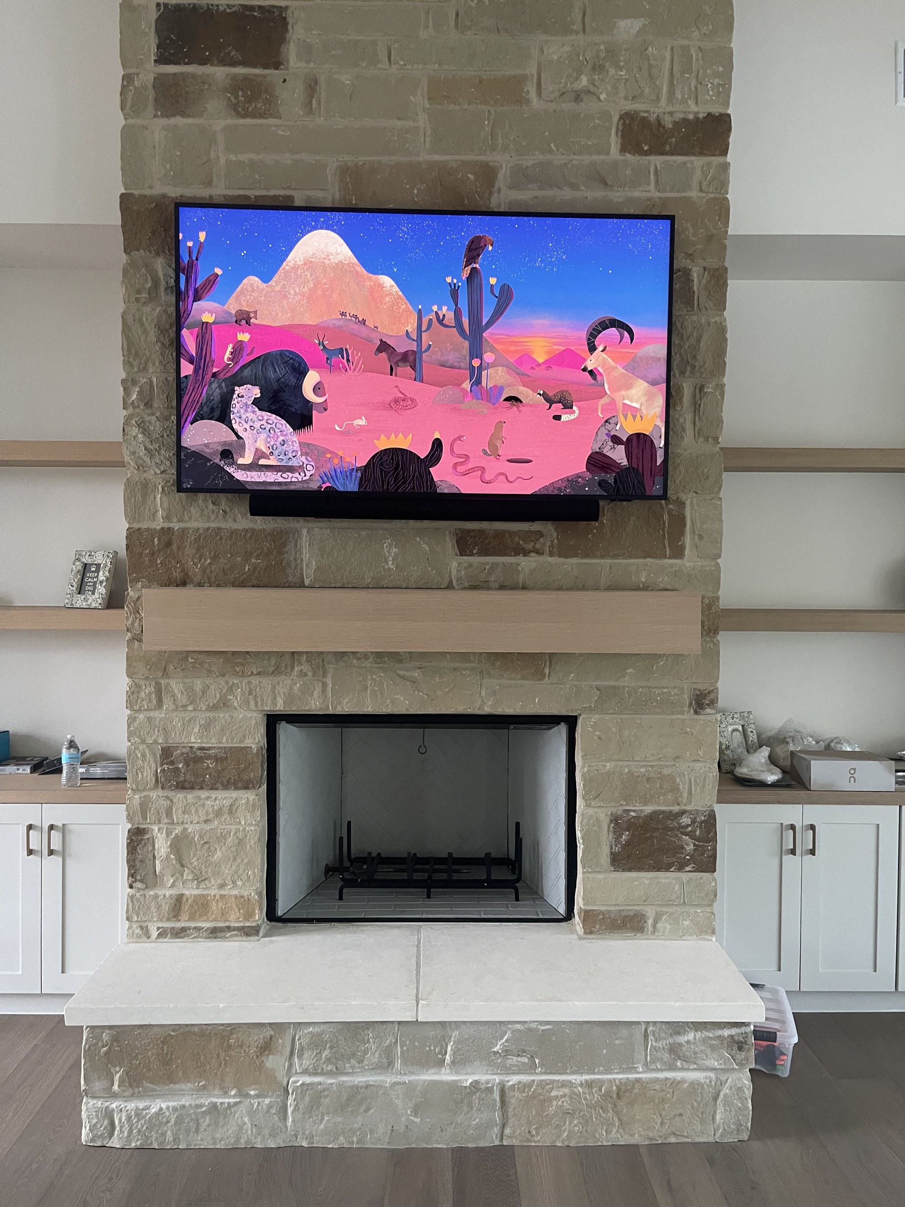Frame TV and soundbar integrated above a stacked stone fireplace