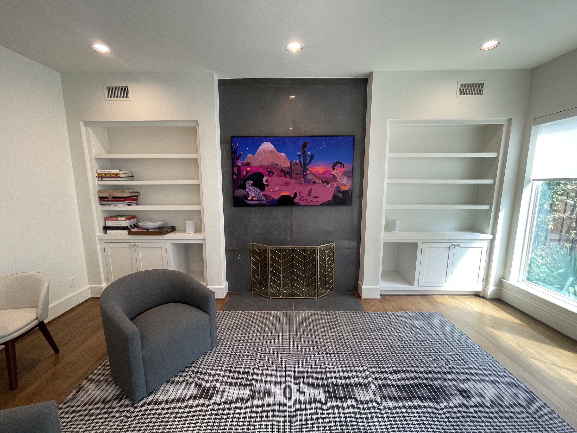 Living room with integrated television, hidden wiring, and built-in shelving