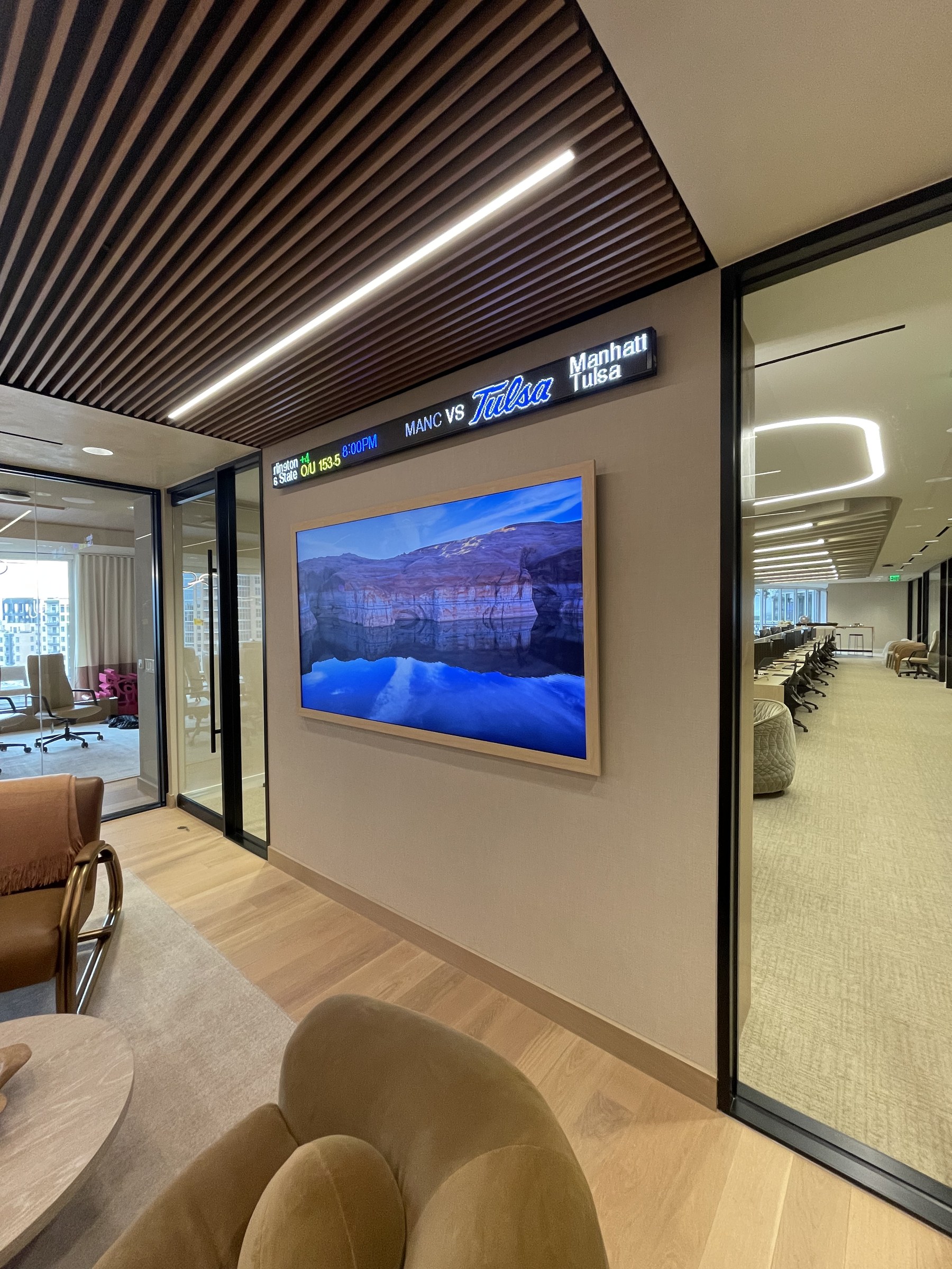 Frame TV integrated beside digital ticker signage in a corporate office corridor