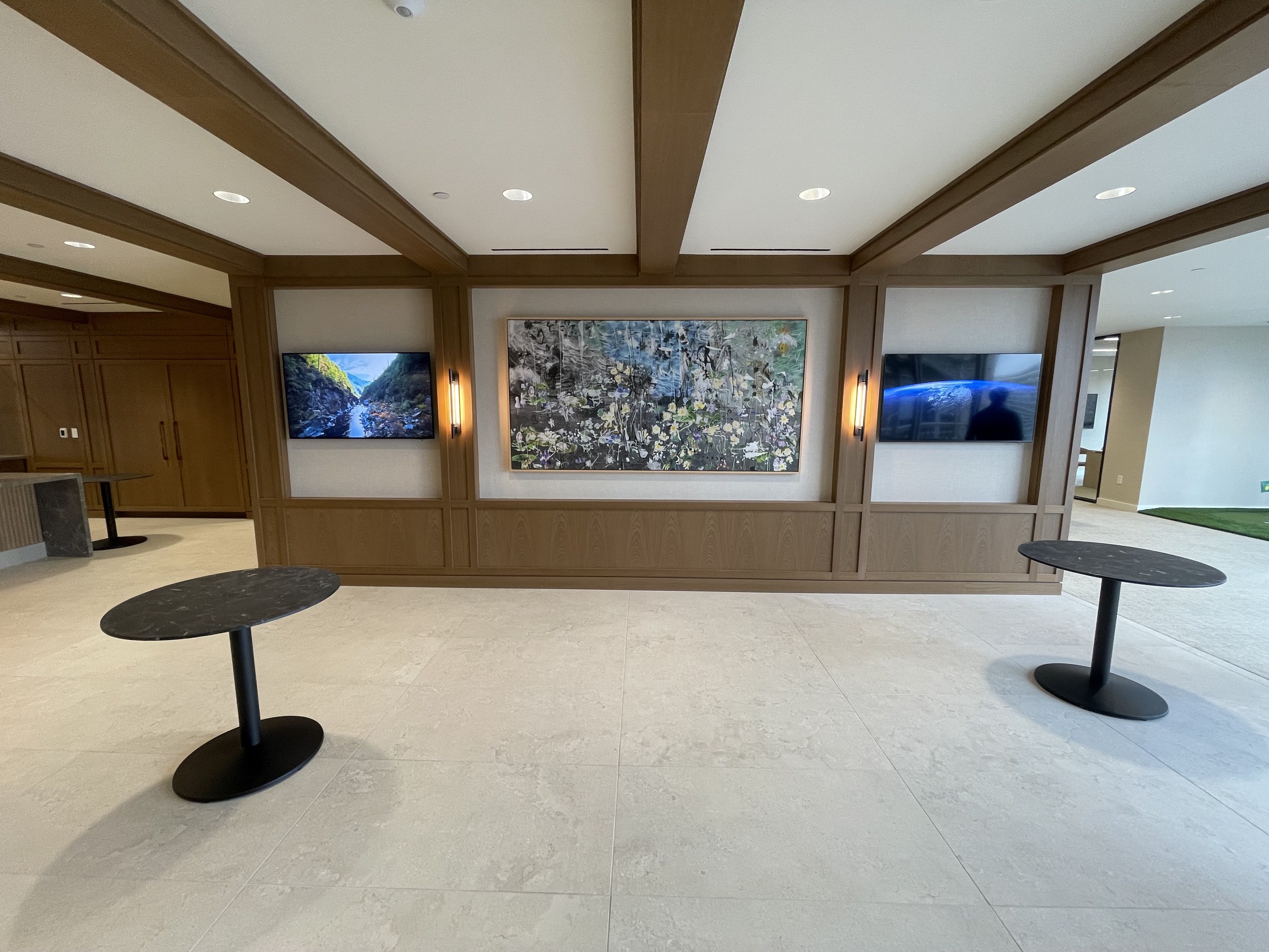 Three integrated displays flanking artwork in a corporate lobby