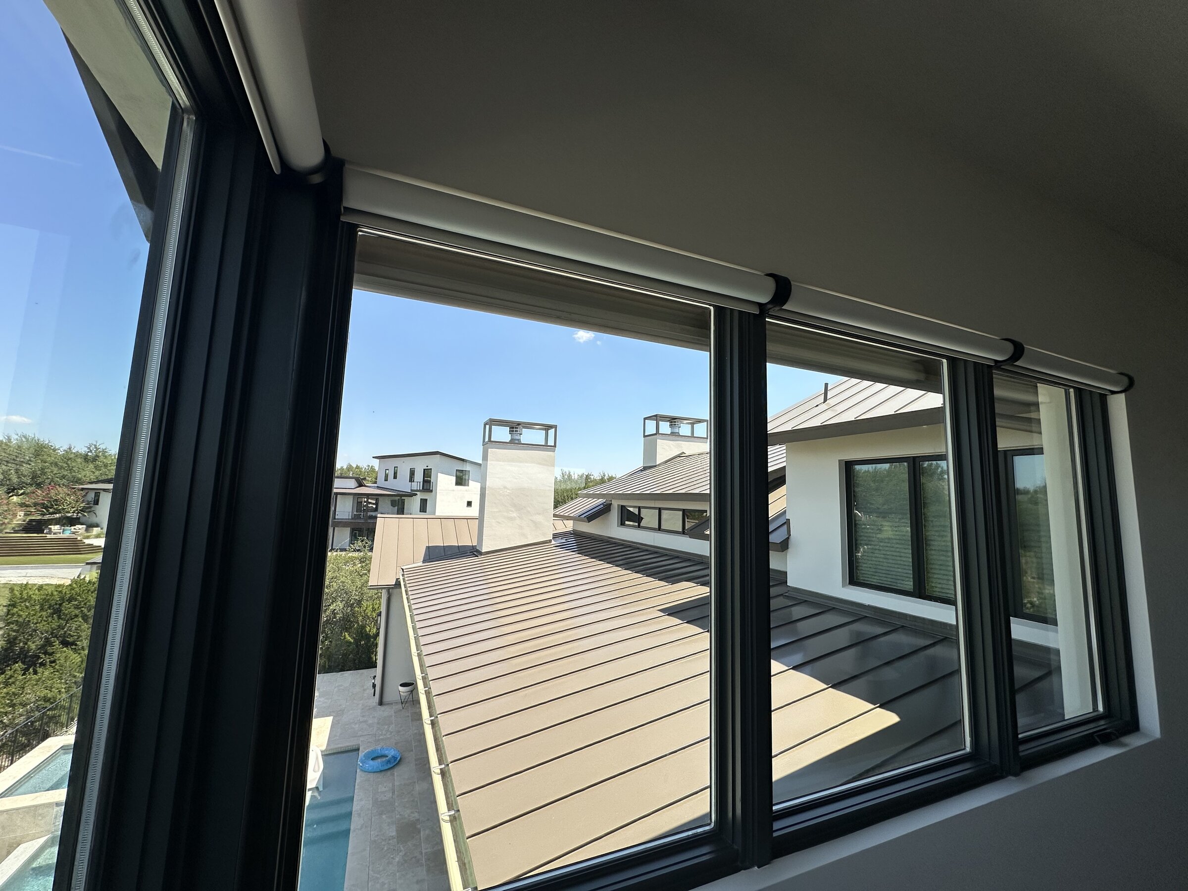 View through motorized roller shades across a rooftop skyline