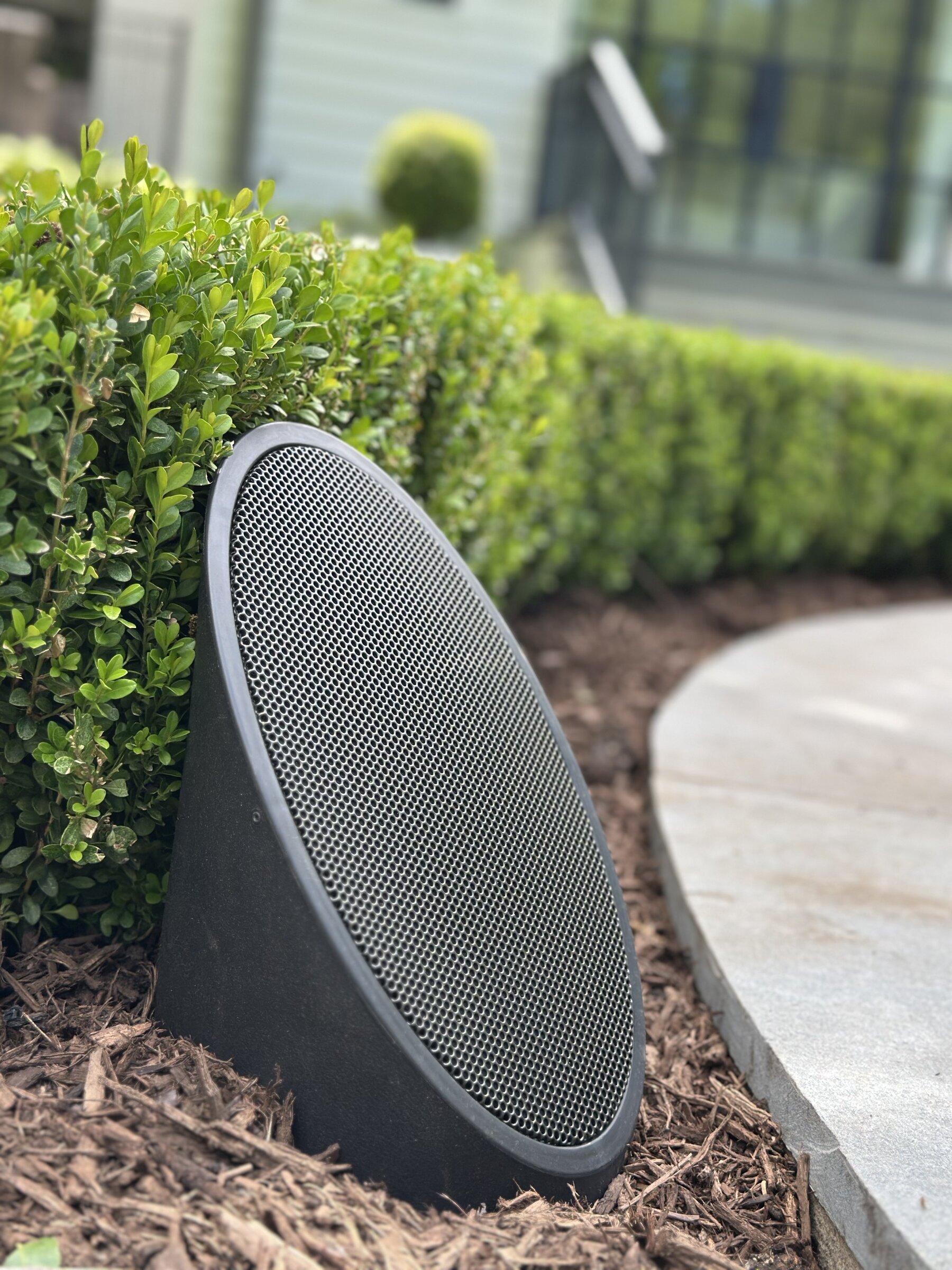 Discreet outdoor landscape speaker tucked into a hedge